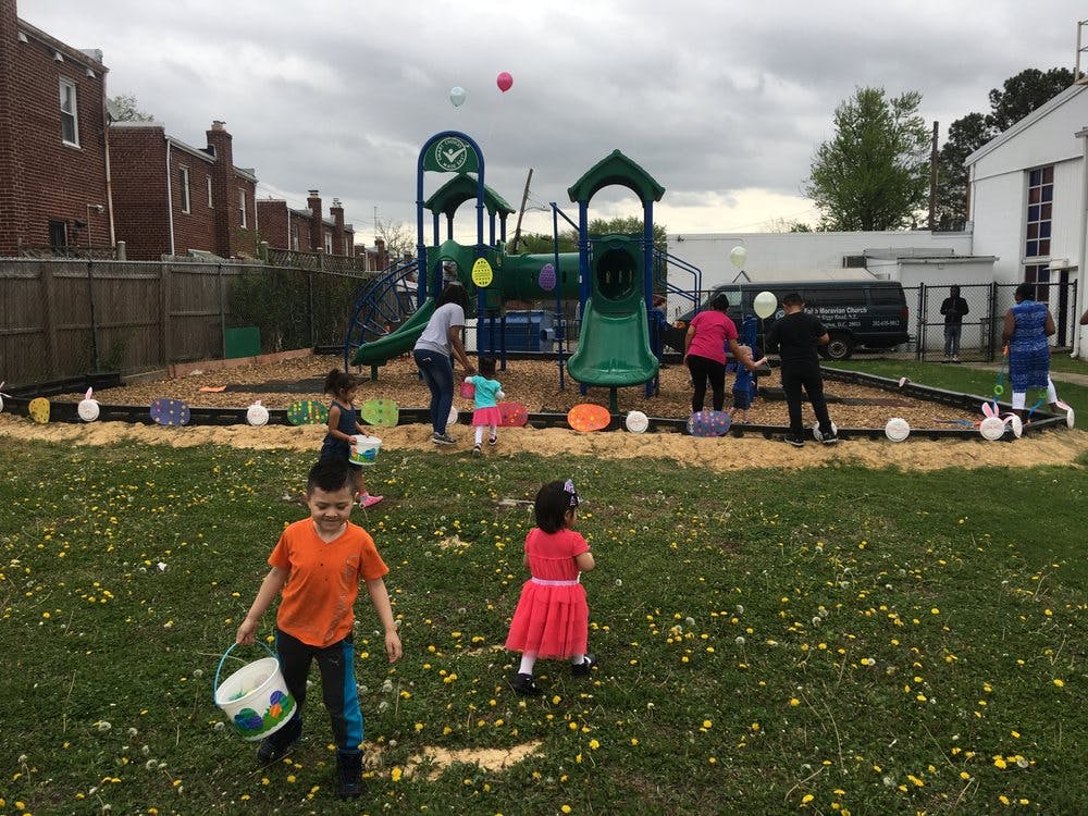 Children and adults on a playground with scattered colorful objects