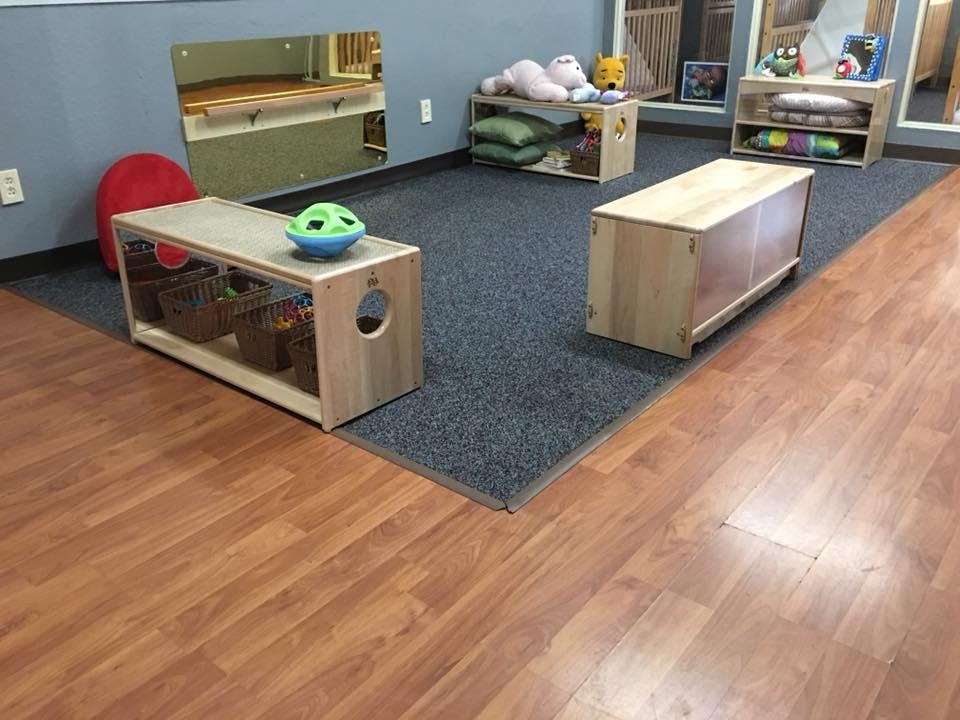 Playroom with wooden storage units on a blue carpet and wood floor