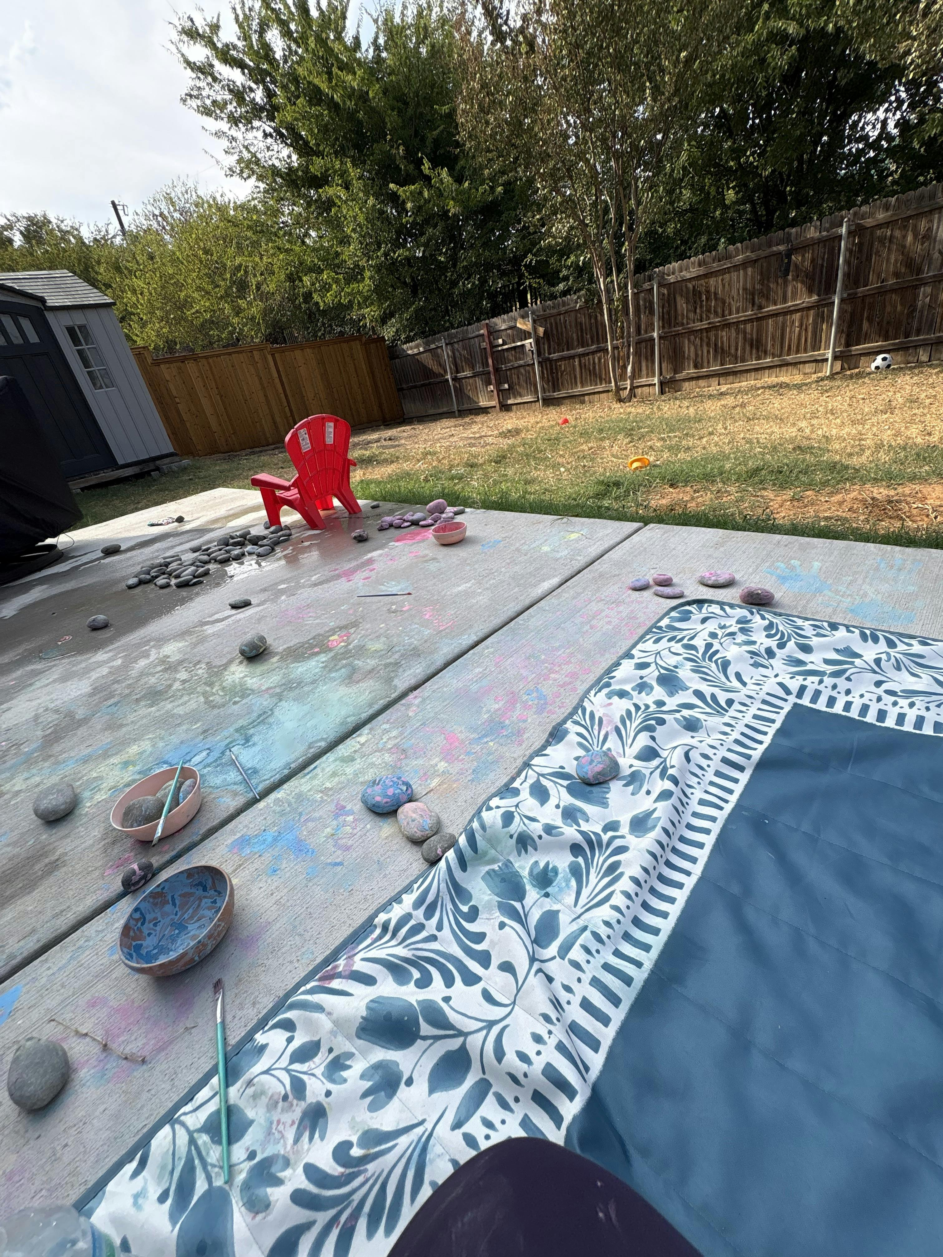 Painted rocks and bowls of paint on a concrete patio