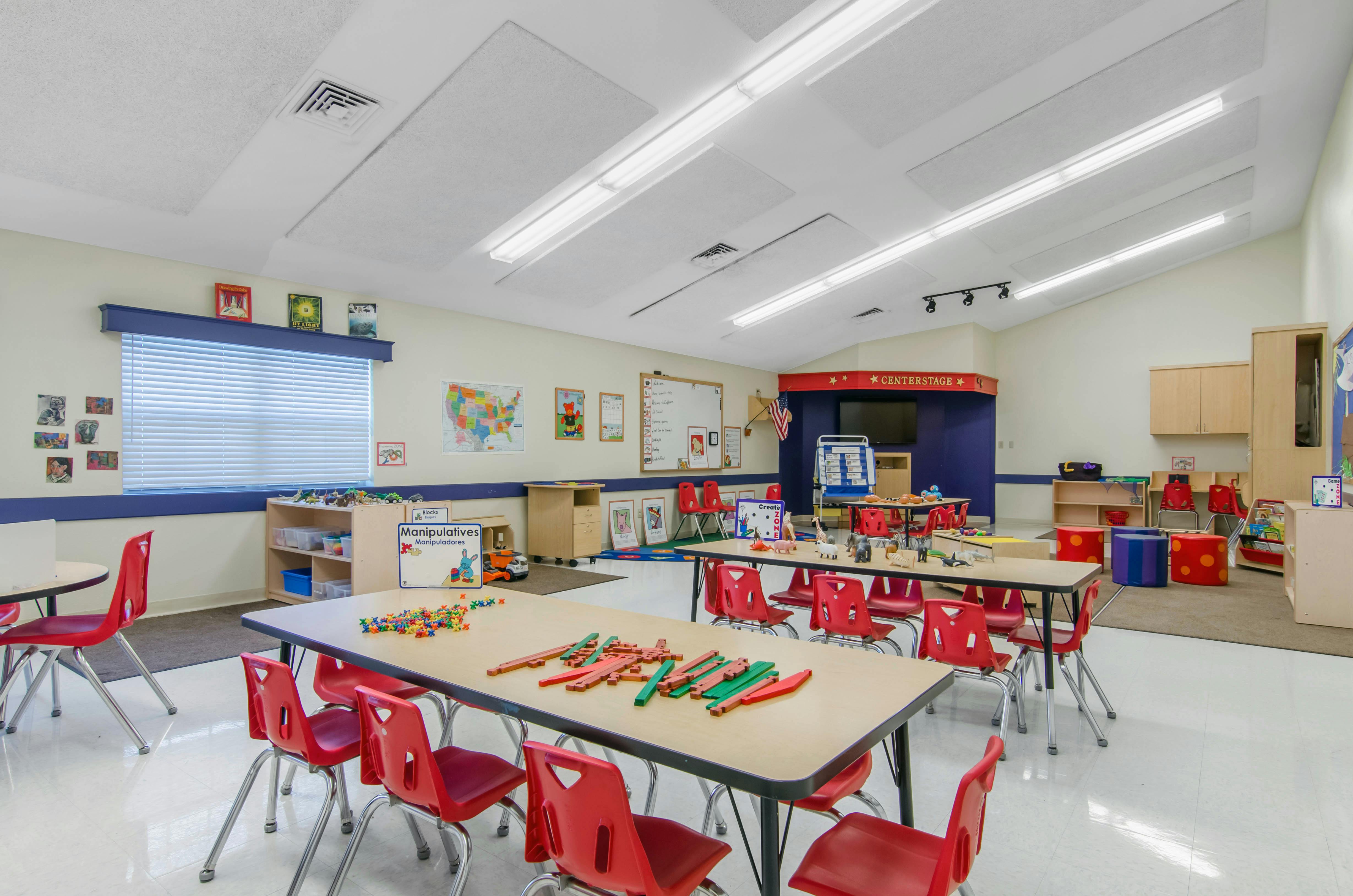 Classroom with children's tables and chairs, educational posters, and activity stations
