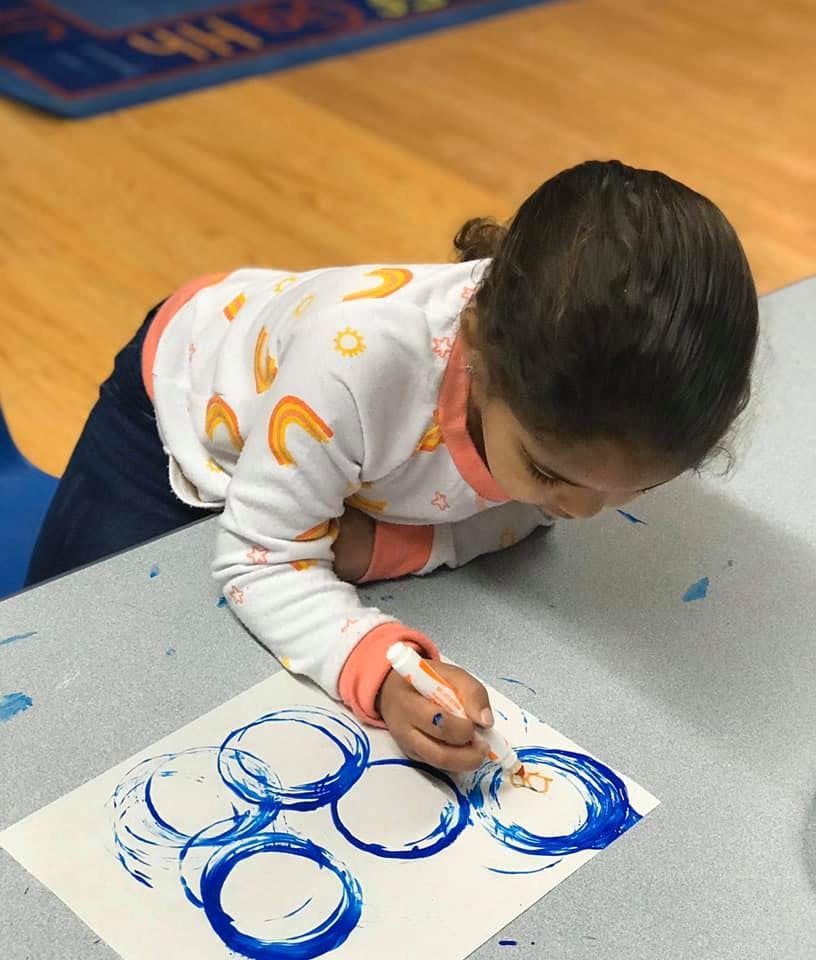 Child painting blue circles on paper