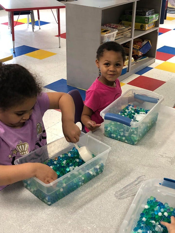 Two children playing with water beads in clear containers