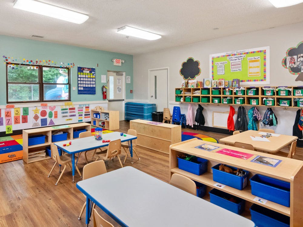 Colorful classroom with small tables and chairs, cubbies, and learning aids