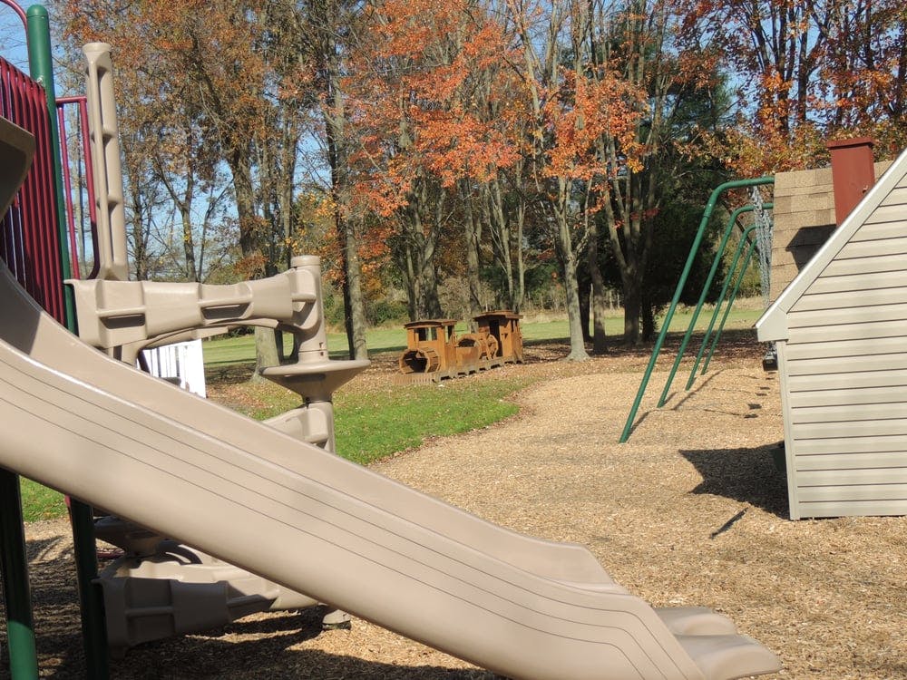 Playground with slide, swings, and wooden train structure