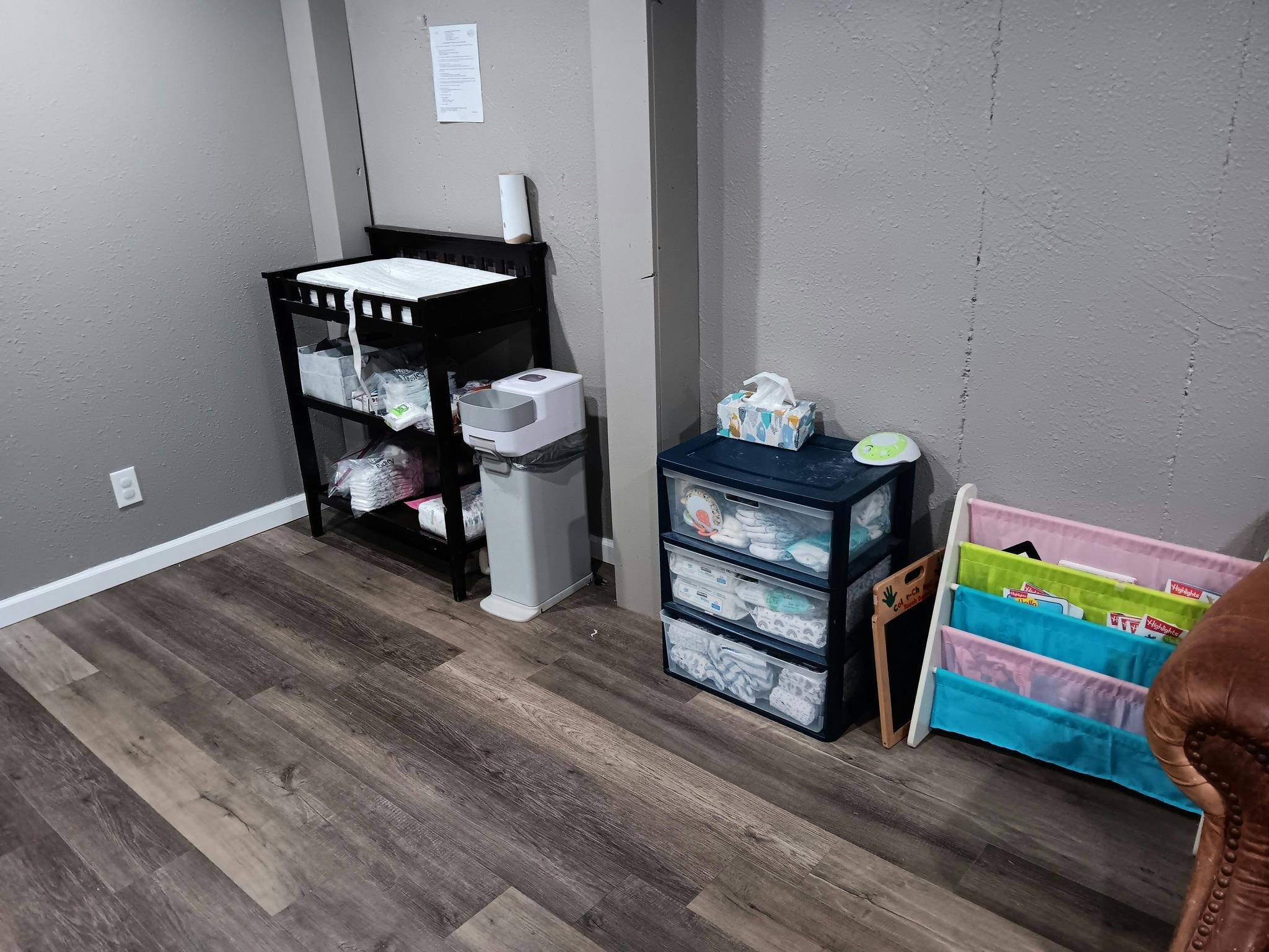 Changing table with supplies next to a storage unit and book sling