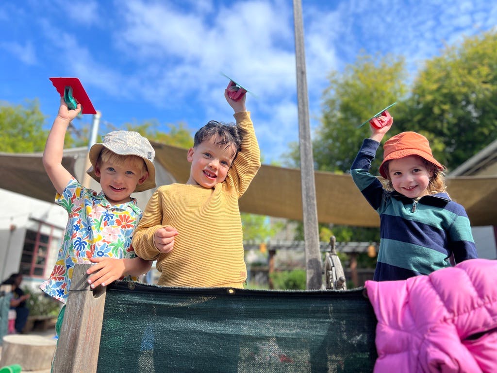 Three children holding up small tools
