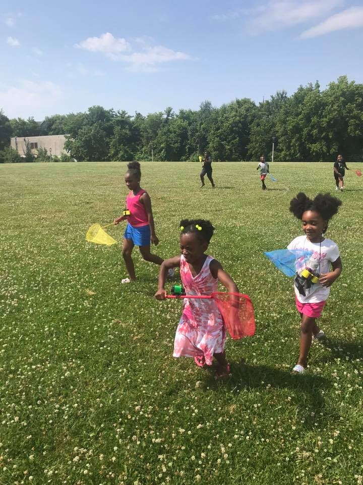 Children running in a grassy field with nets
