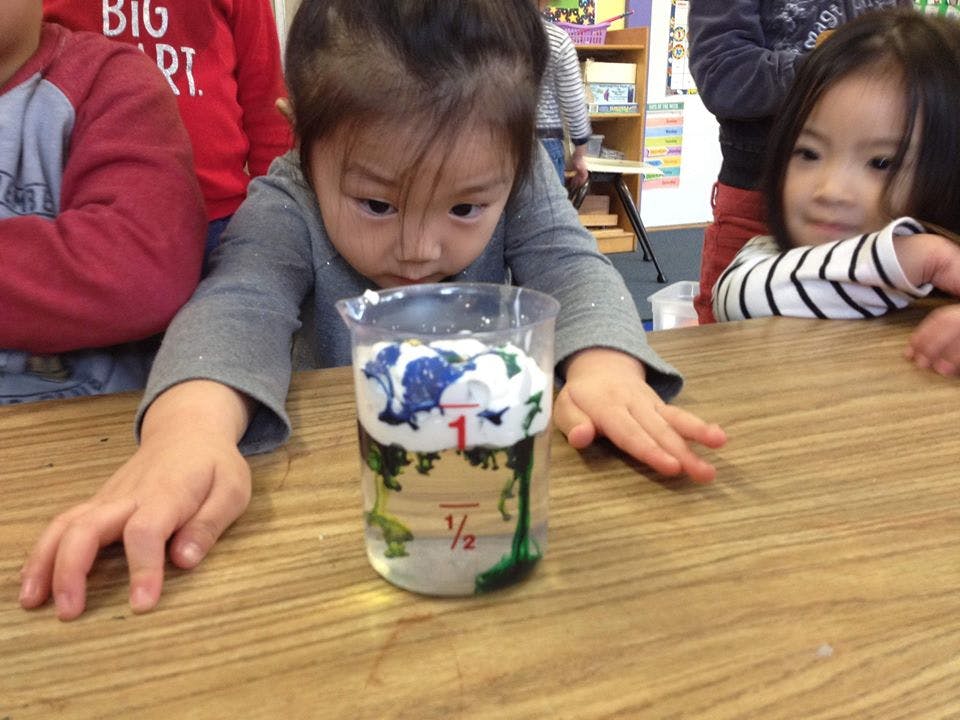 Child looking at a beaker with liquid and white foam