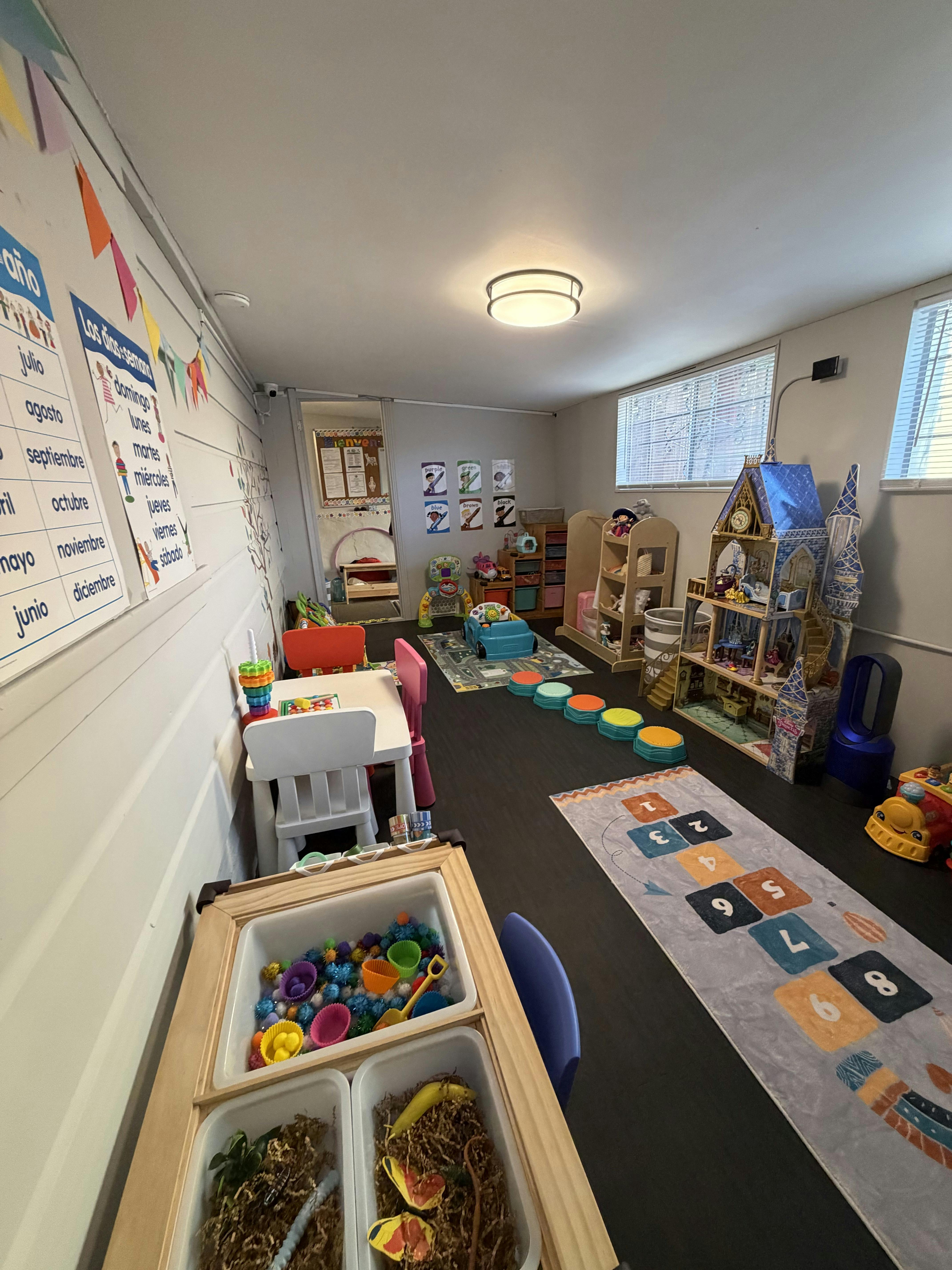 A colorful children's play room with tables, chairs, toys, and educational posters