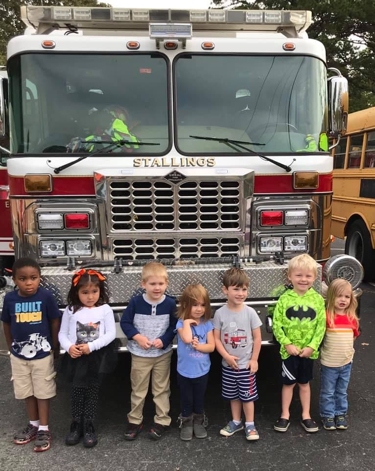 Six children standing in front of a fire truck