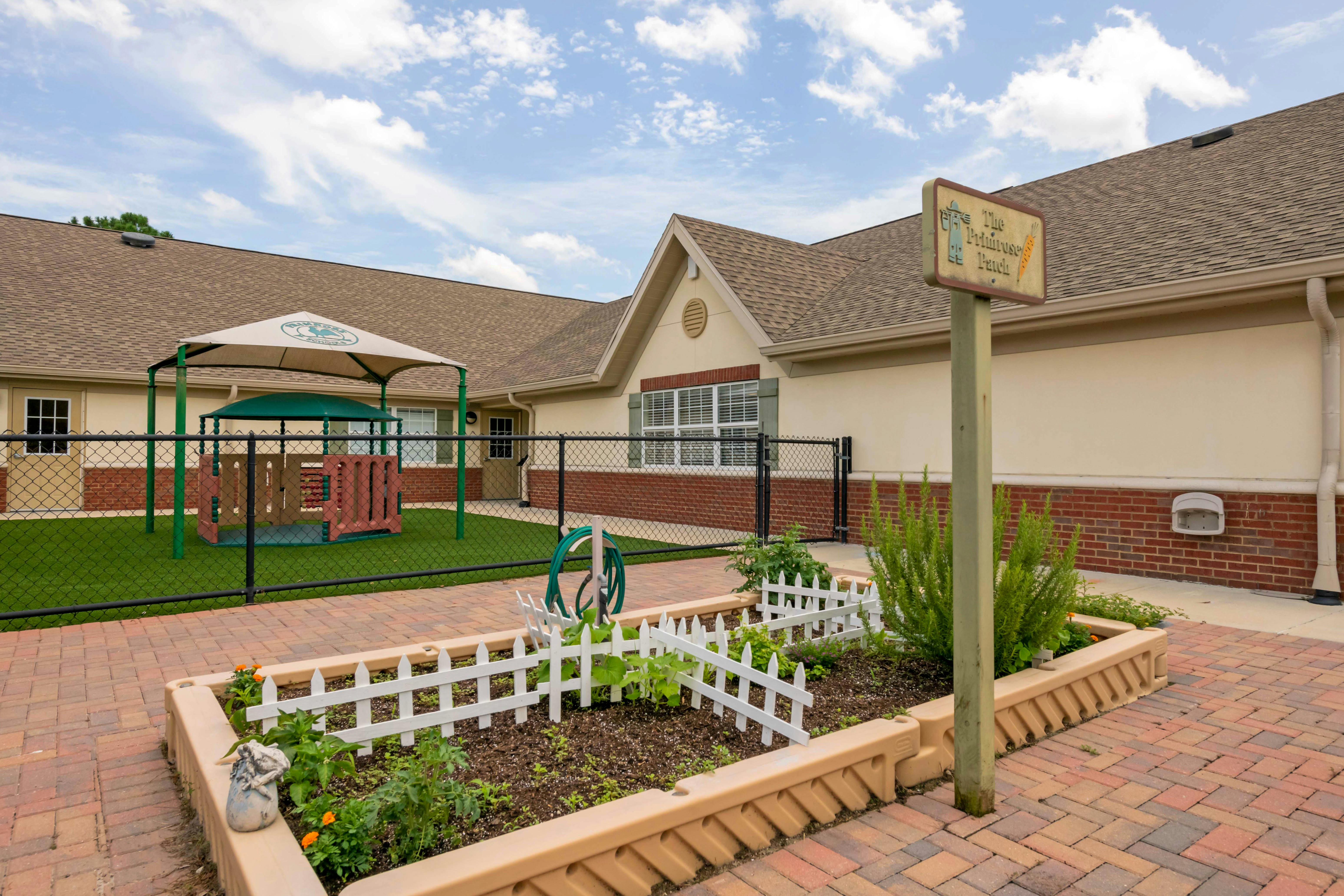 Building exterior with a fenced playground and raised garden bed