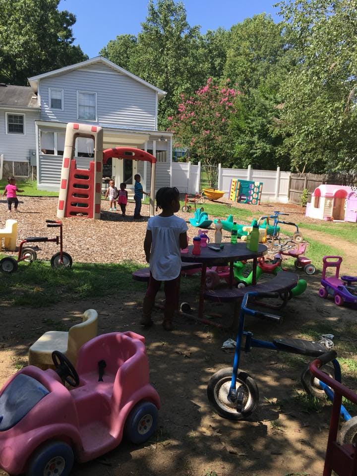 Children playing in a backyard with various toys and a slide