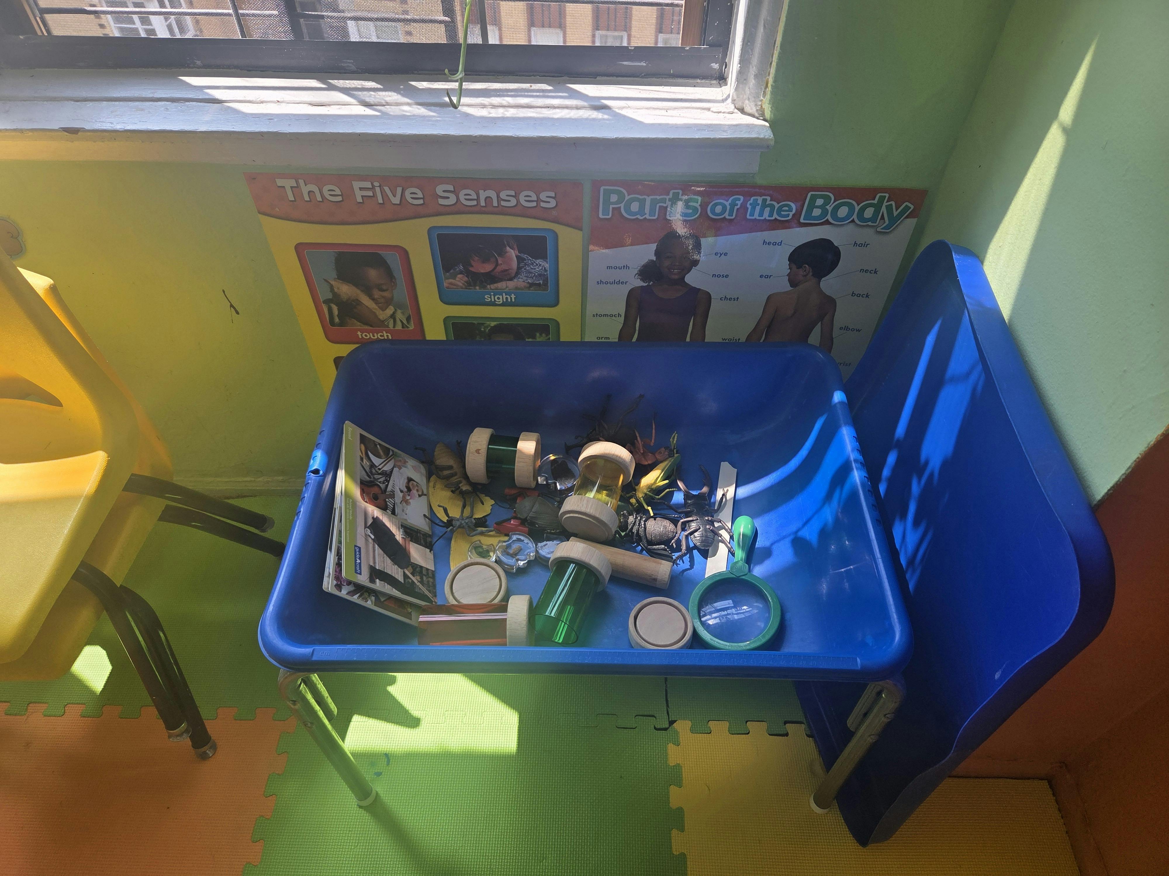 Blue bin filled with various objects on a colorful floor
