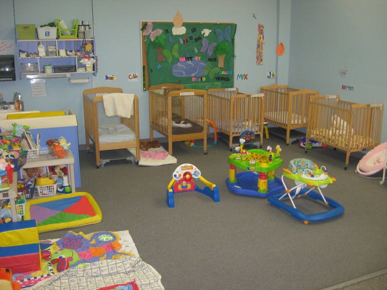 Nursery room with multiple cribs and baby play equipment