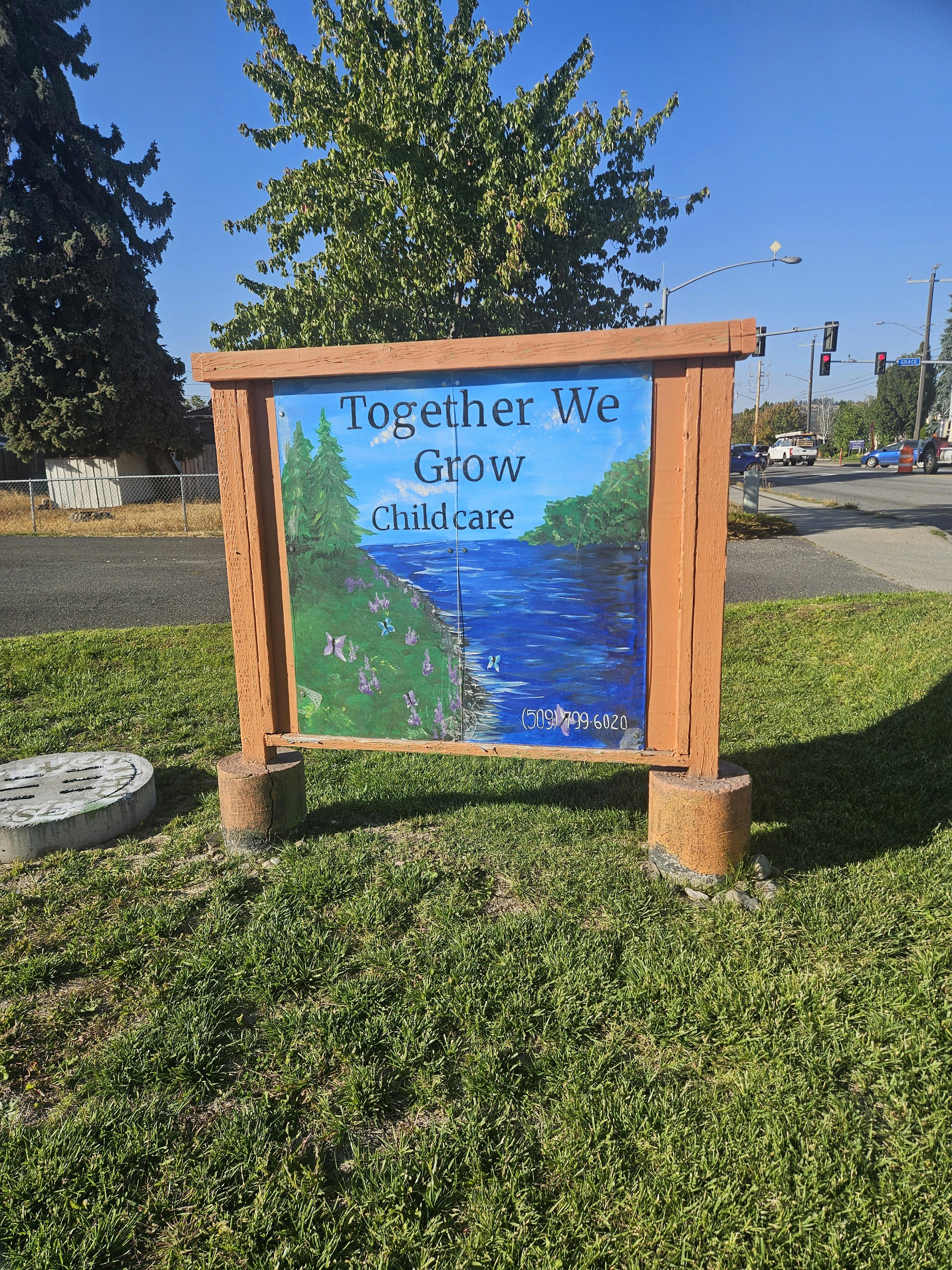 Sign with "Together We Grow Child care" text and a painted river scene