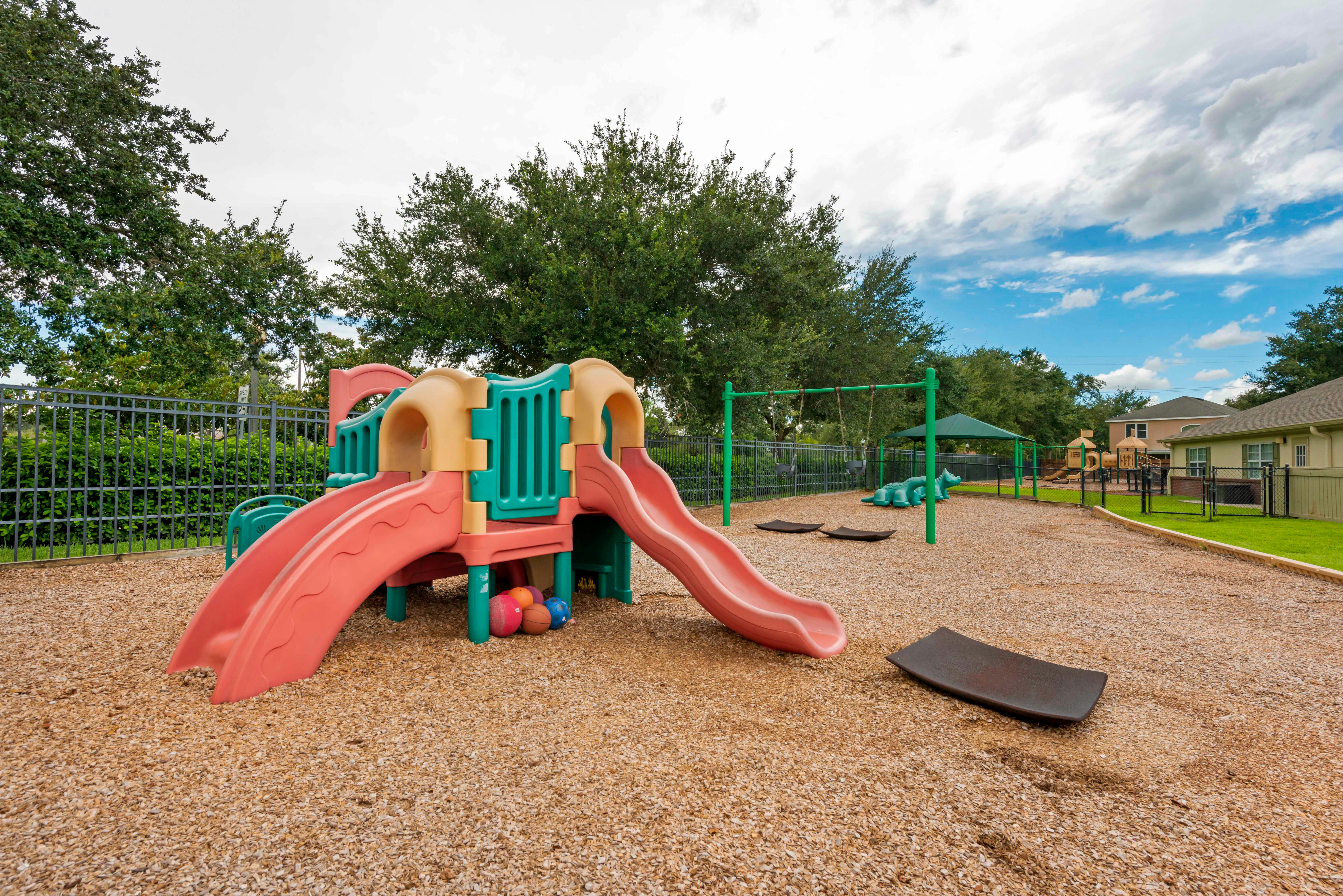 A colorful playground with slides and swings on wood chips