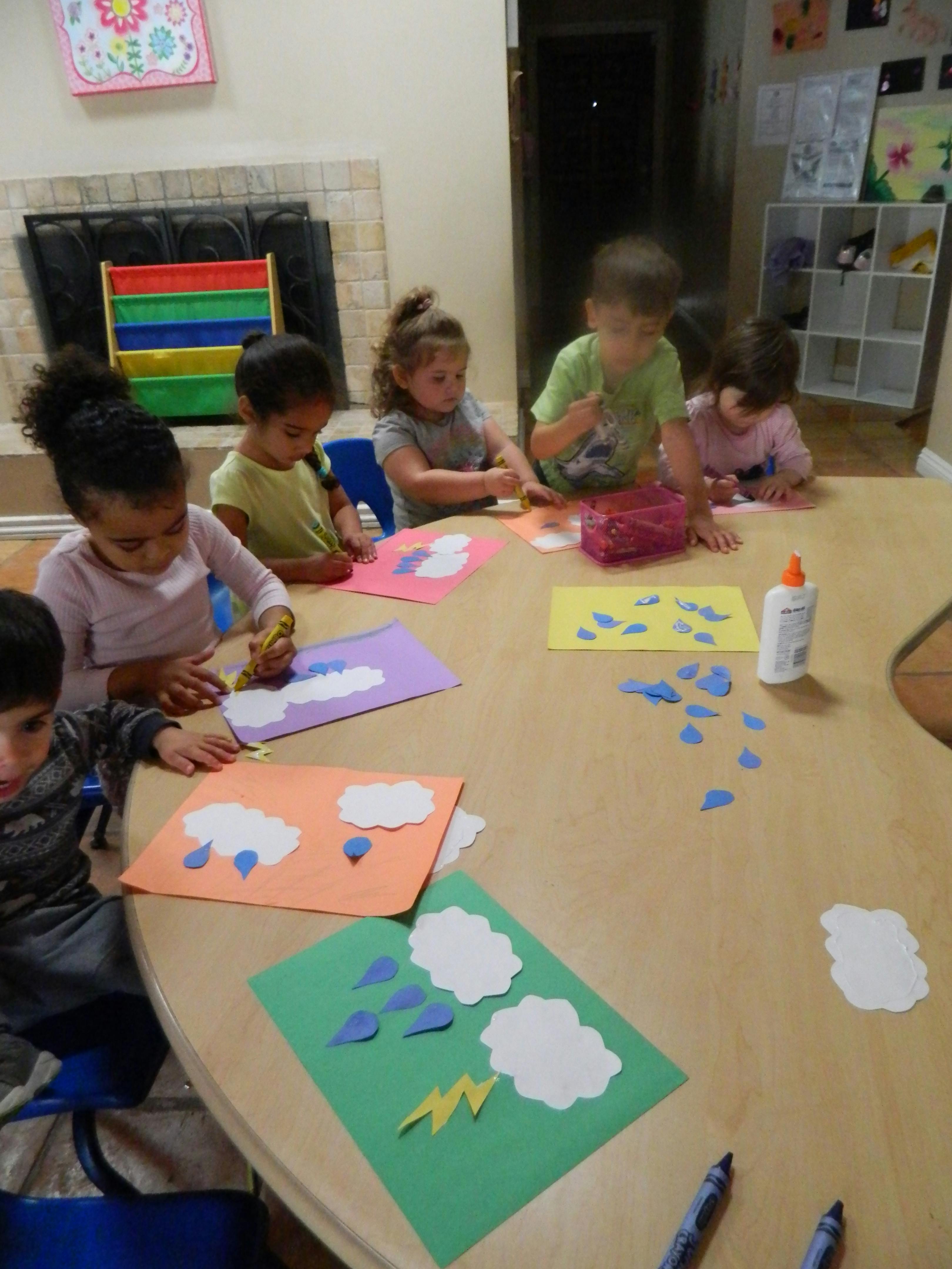 Children sitting at a table doing crafts with paper crafts