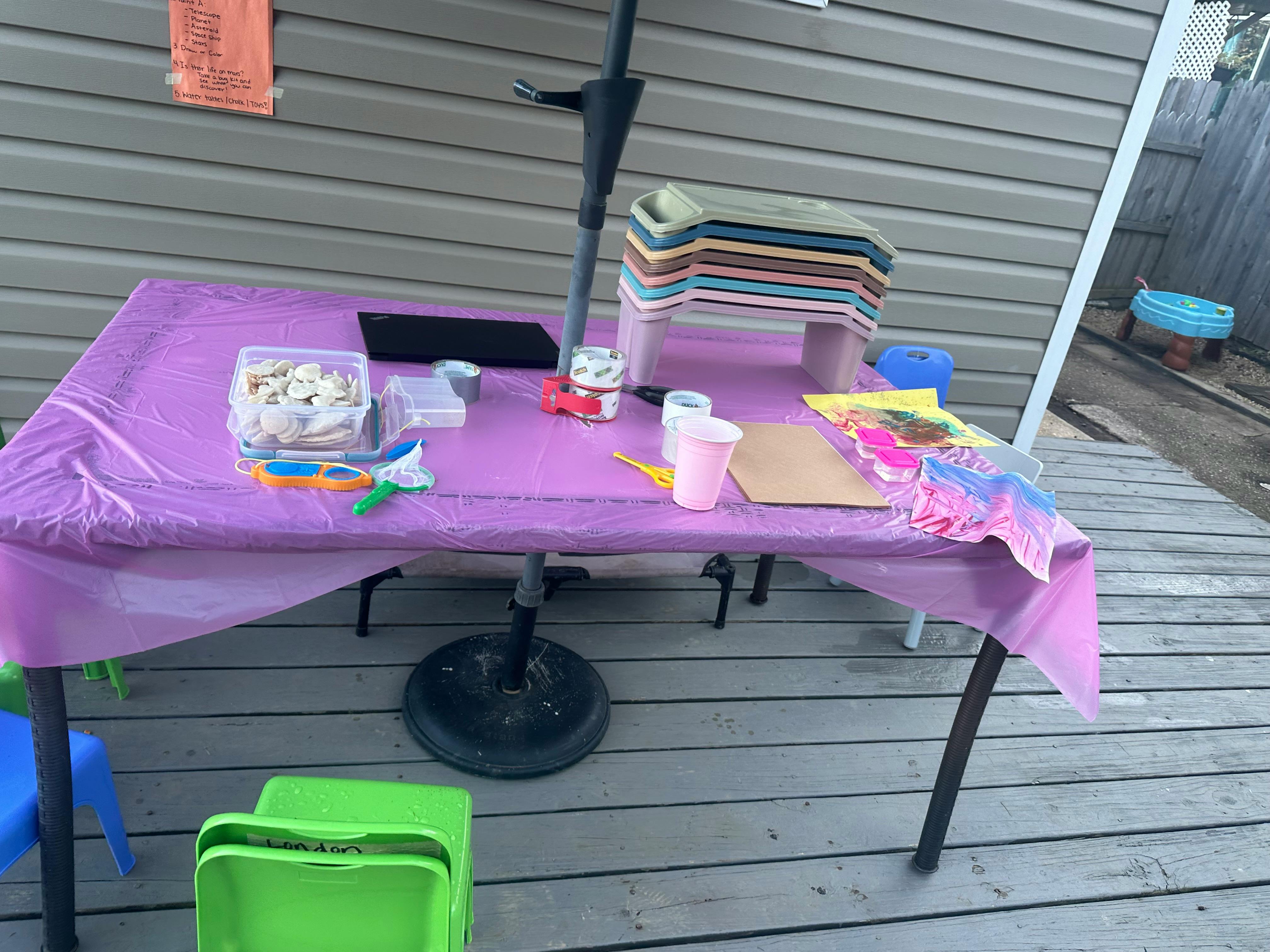 Table with purple tablecloth and various items on a wooden deck