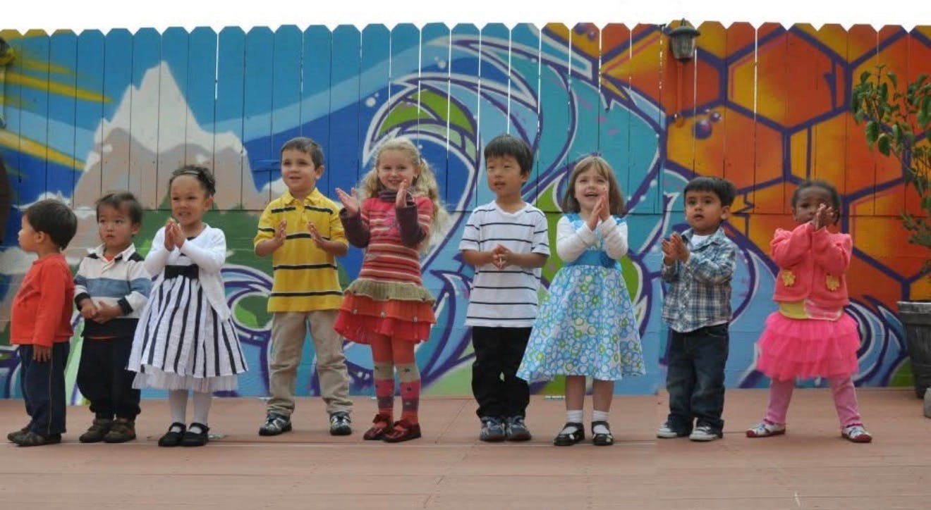 Group of children standing in a row in front of a colorful mural
