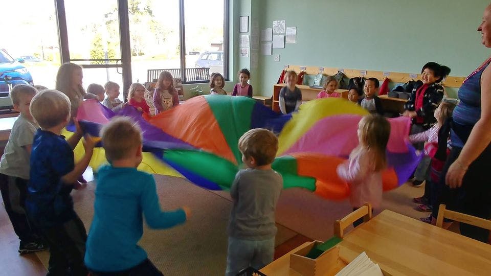 Children playing with a colorful parachute
