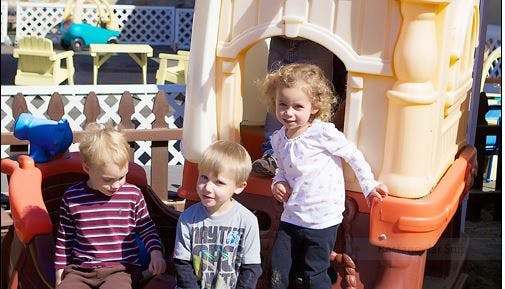 Three children playing on an outdoor play structure