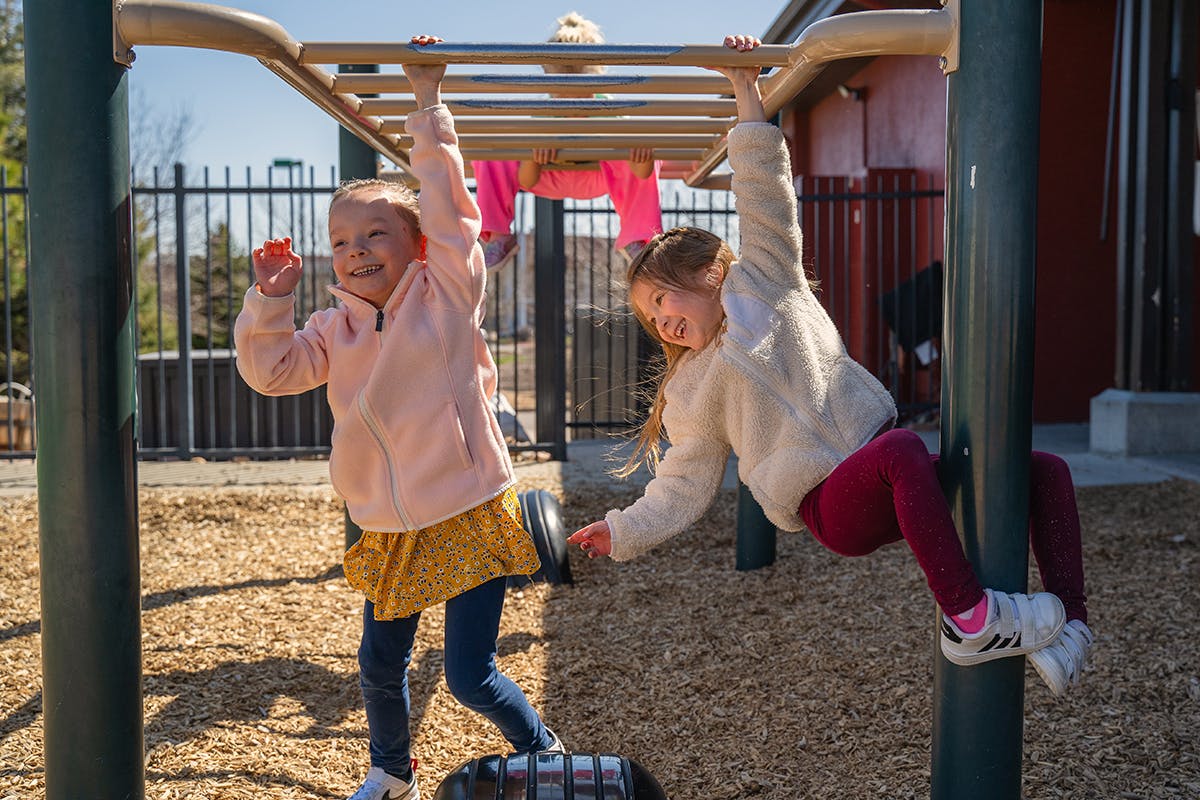 Two children playing on monkey bars at a playground