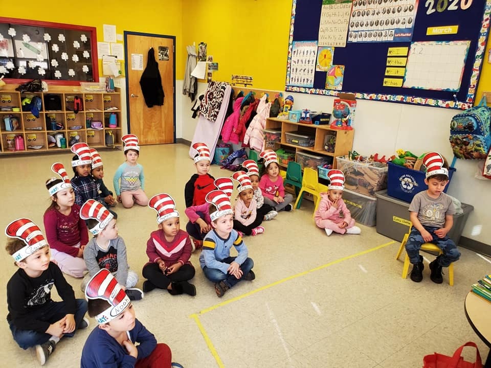 Children wearing striped hats sitting on the floor in a classroom