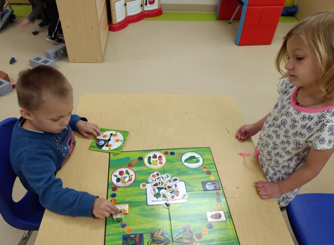 Two children playing a board game at a table