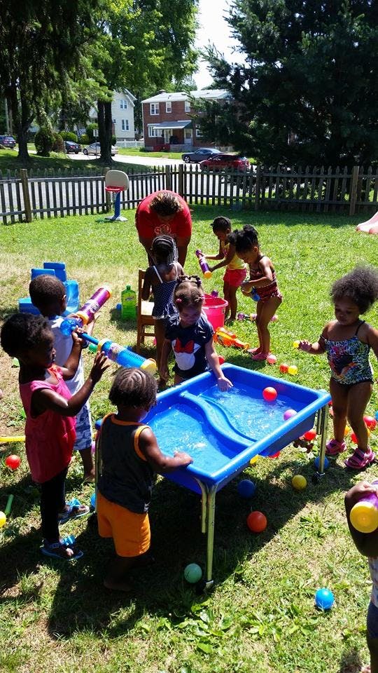 Adult and children playing with water toys in a grassy yard