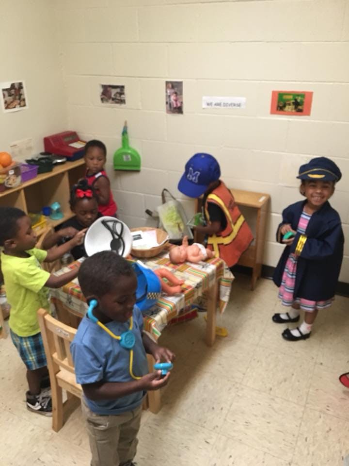 Children playing with toys and dress-up clothes in a classroom