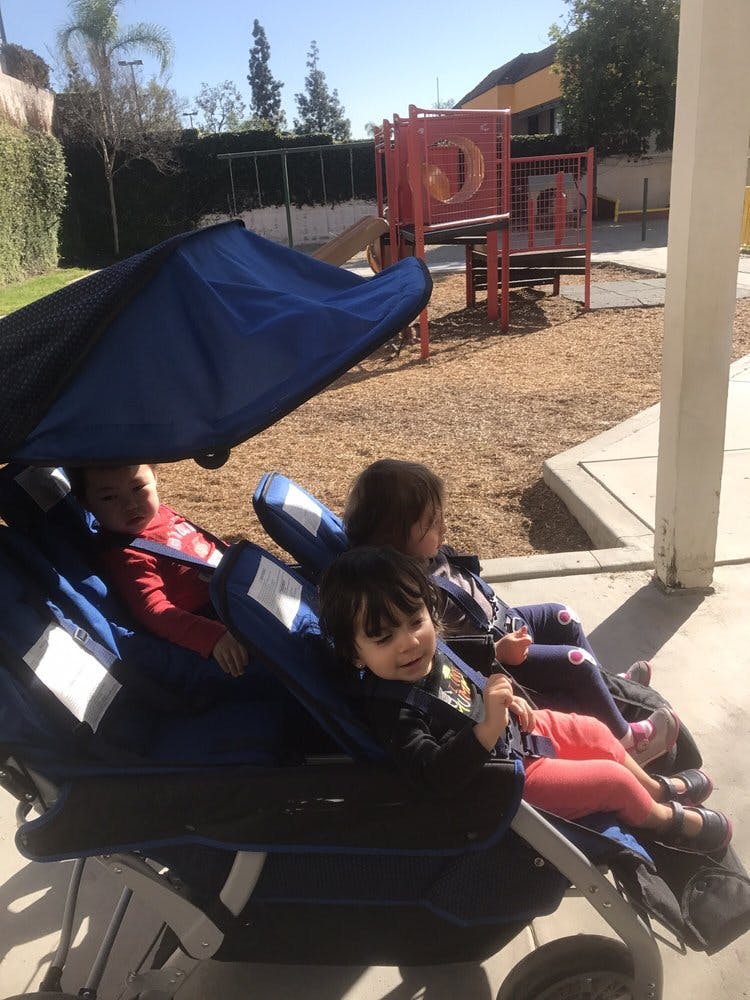 Three children in a stroller on a playground
