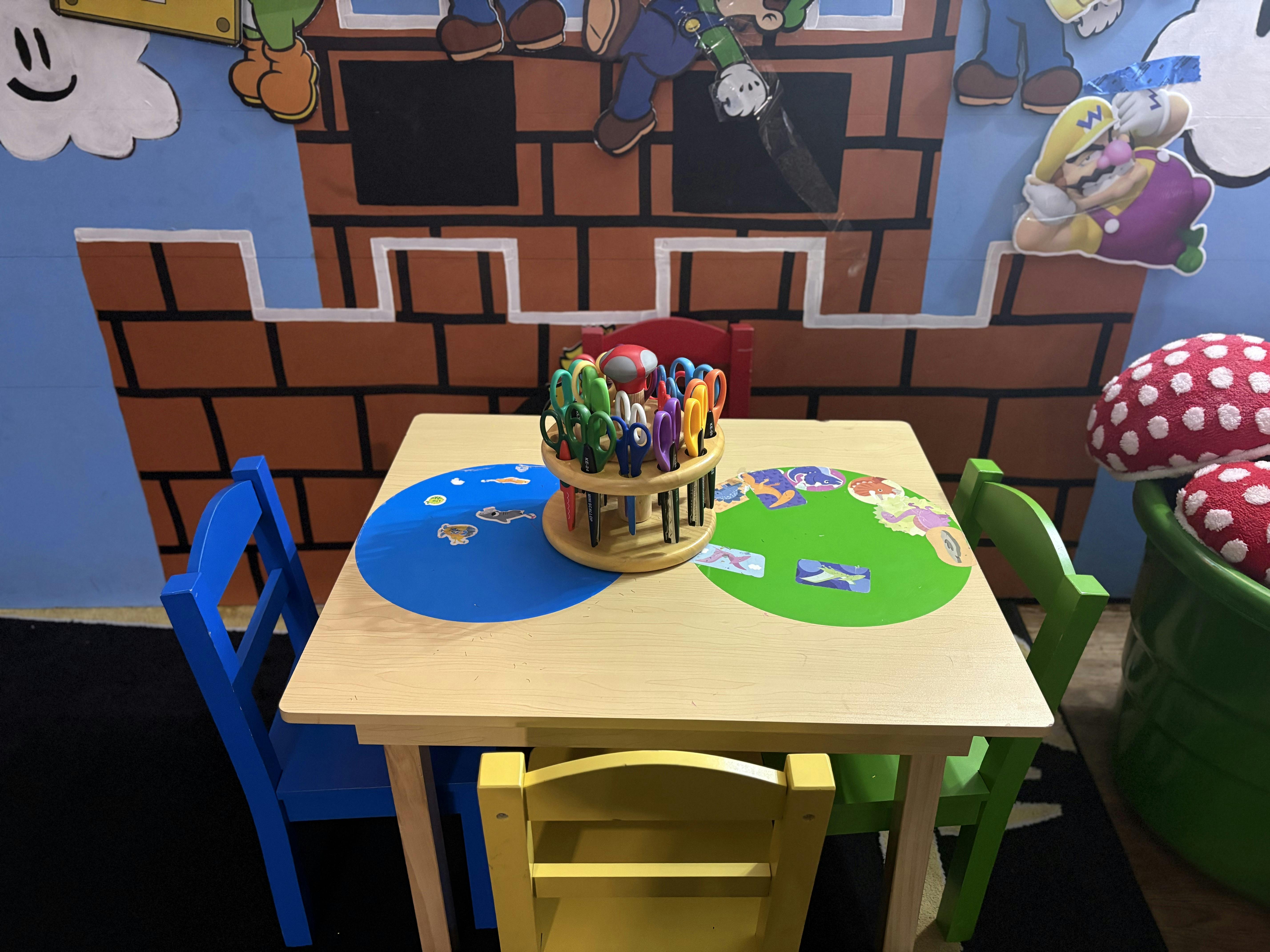 Small wooden table with scissors in a holder in a colorful classroom