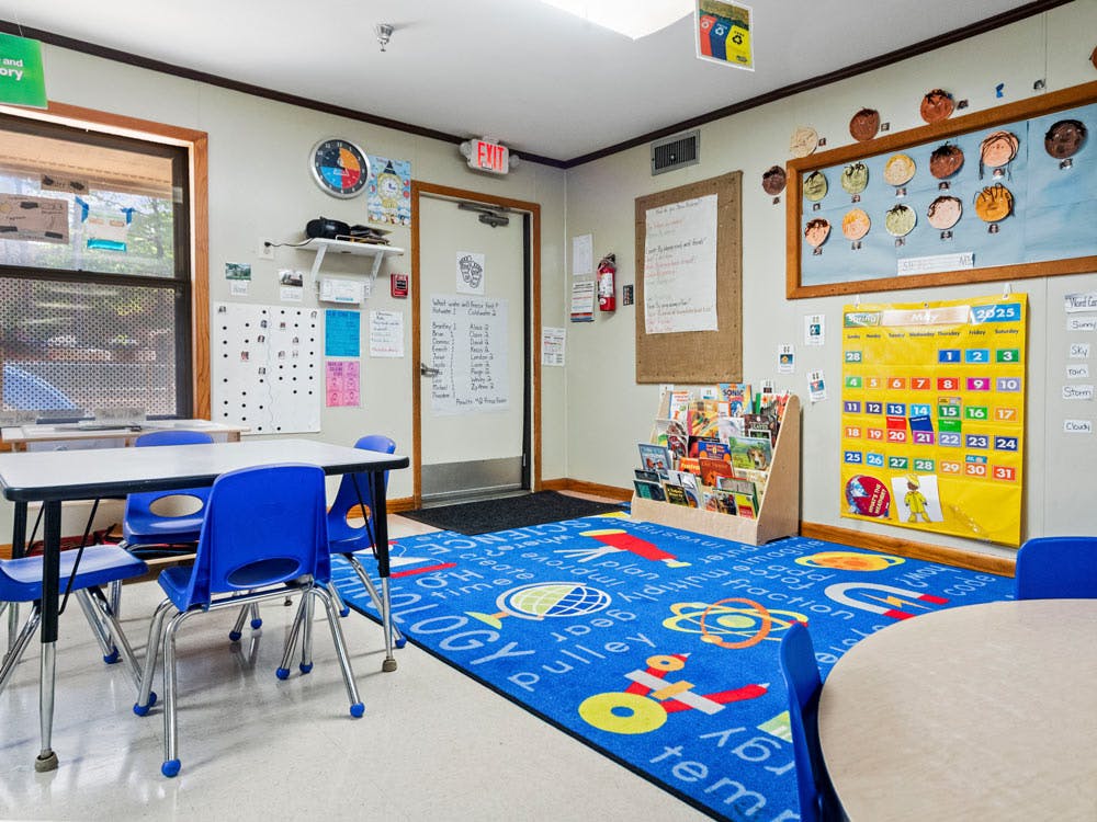 Classroom with tables, chairs, and educational posters on the walls