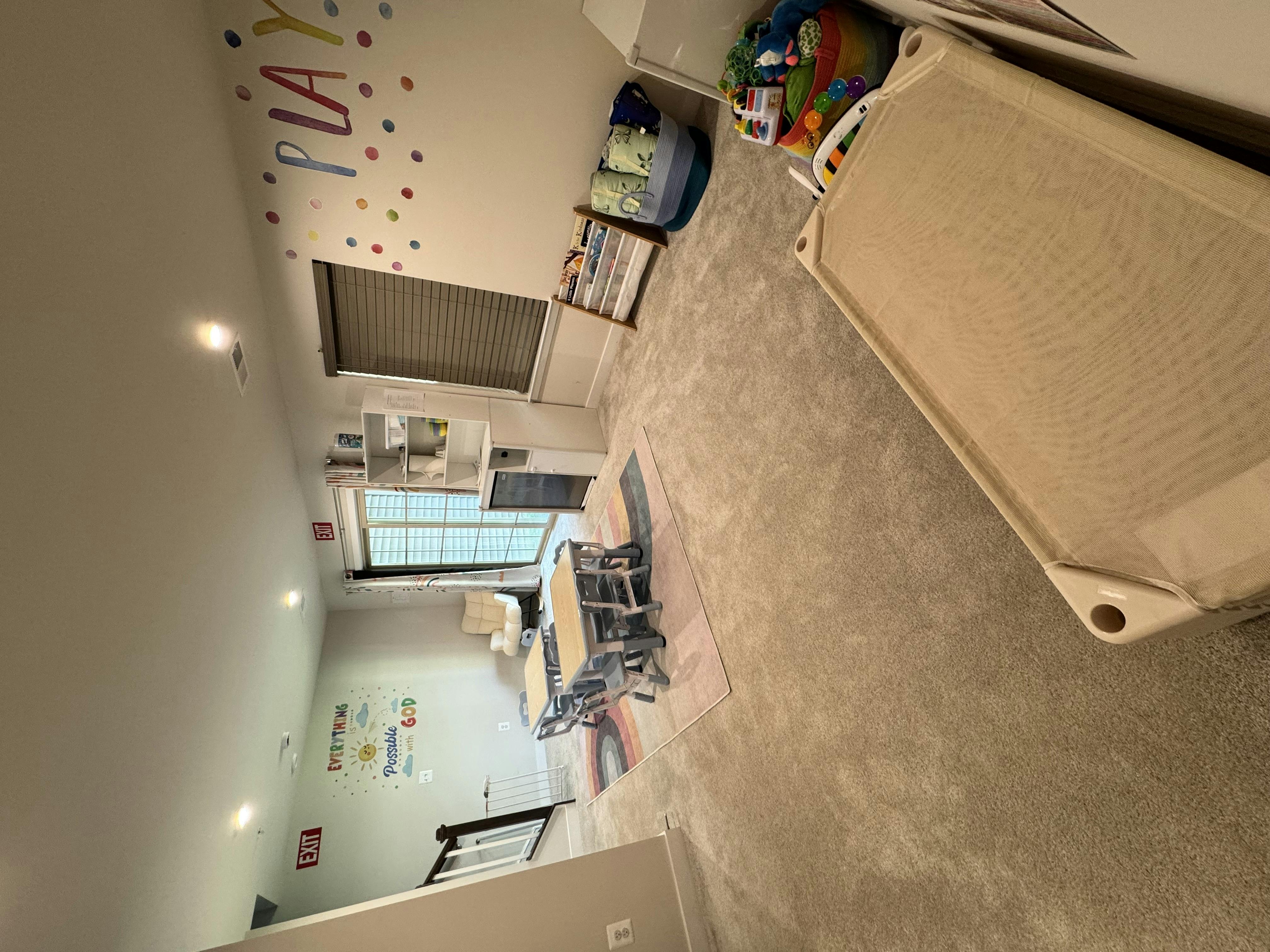 Child's room with a cot, small table and chairs, and wall decor