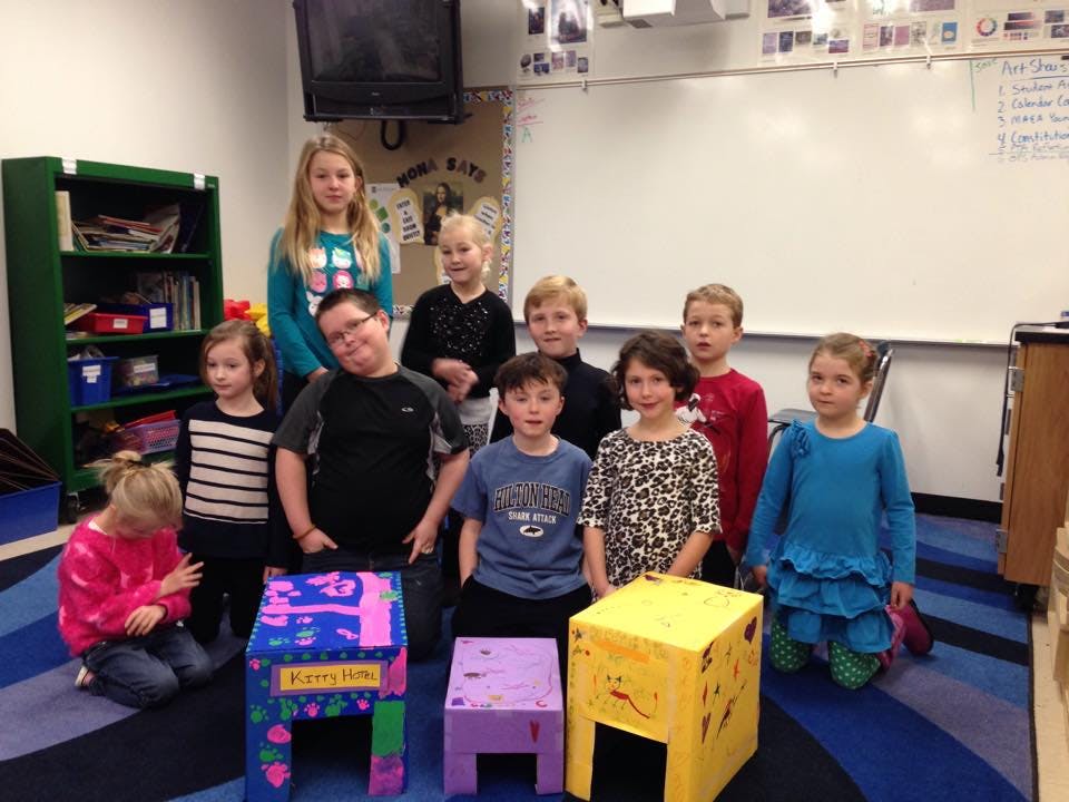 Group of children and teens posing with decorated boxes in a classroom