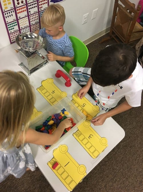 Three children playing with counting toys at a table