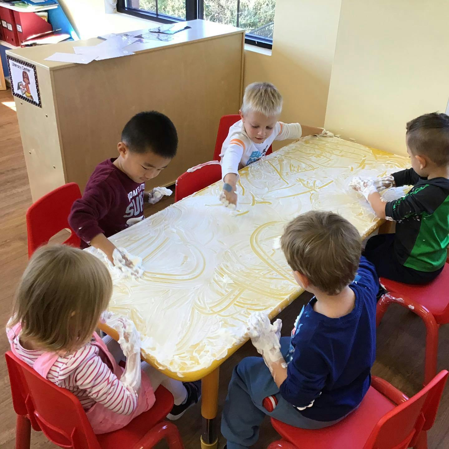 Children playing with a sensory material on a table in a classroom