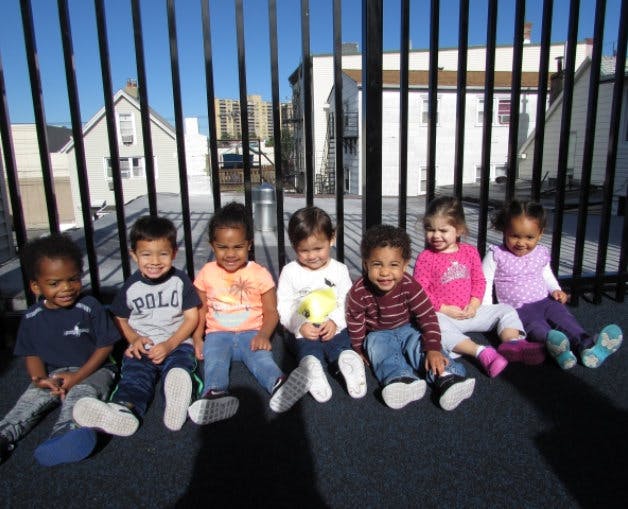 Six children sitting in a row outdoors