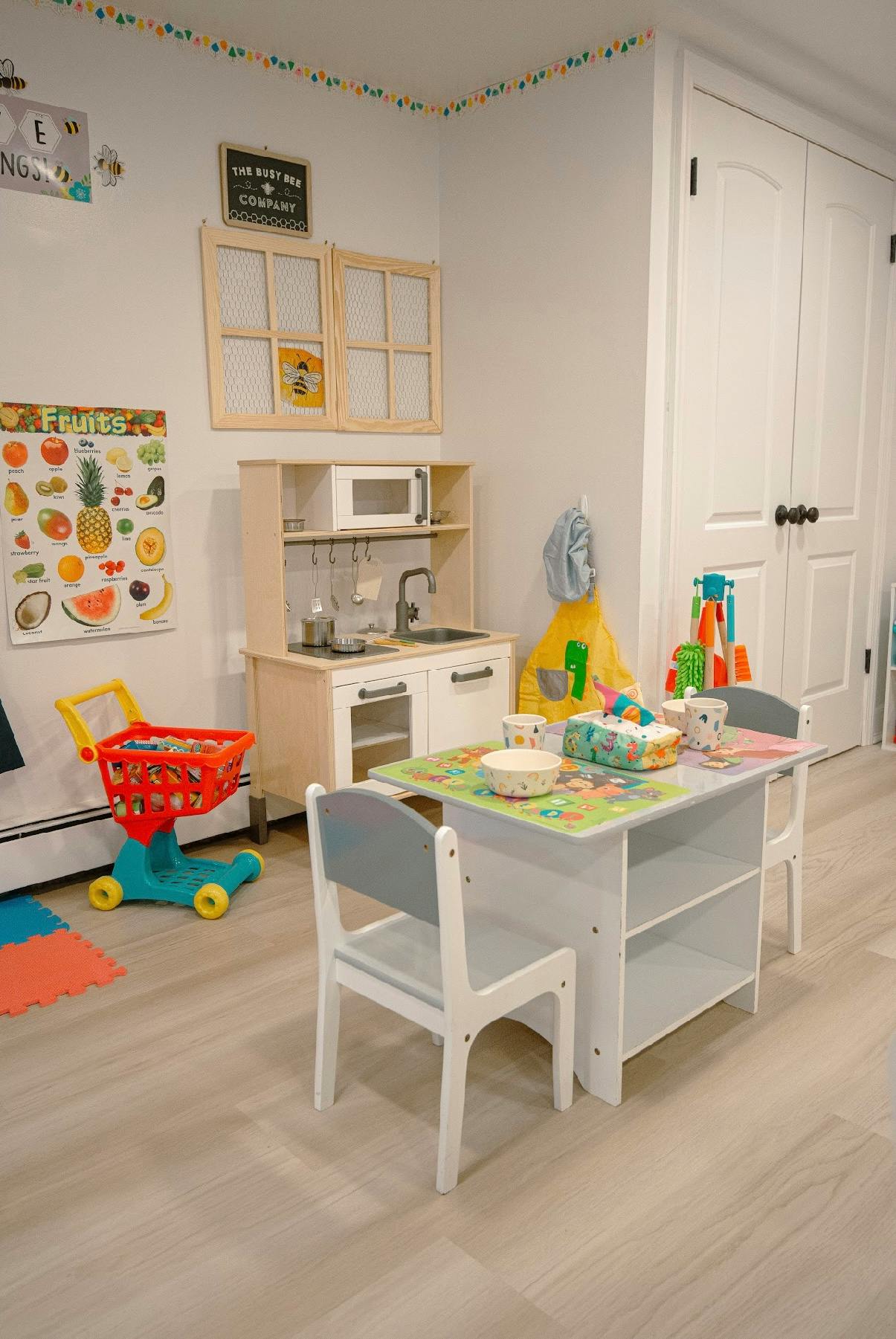 Playroom with toy kitchen, small table and chairs, and shopping cart