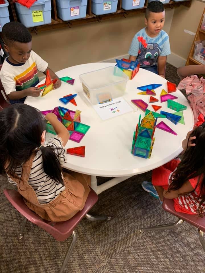 Children playing with colorful magnetic tiles at a round table