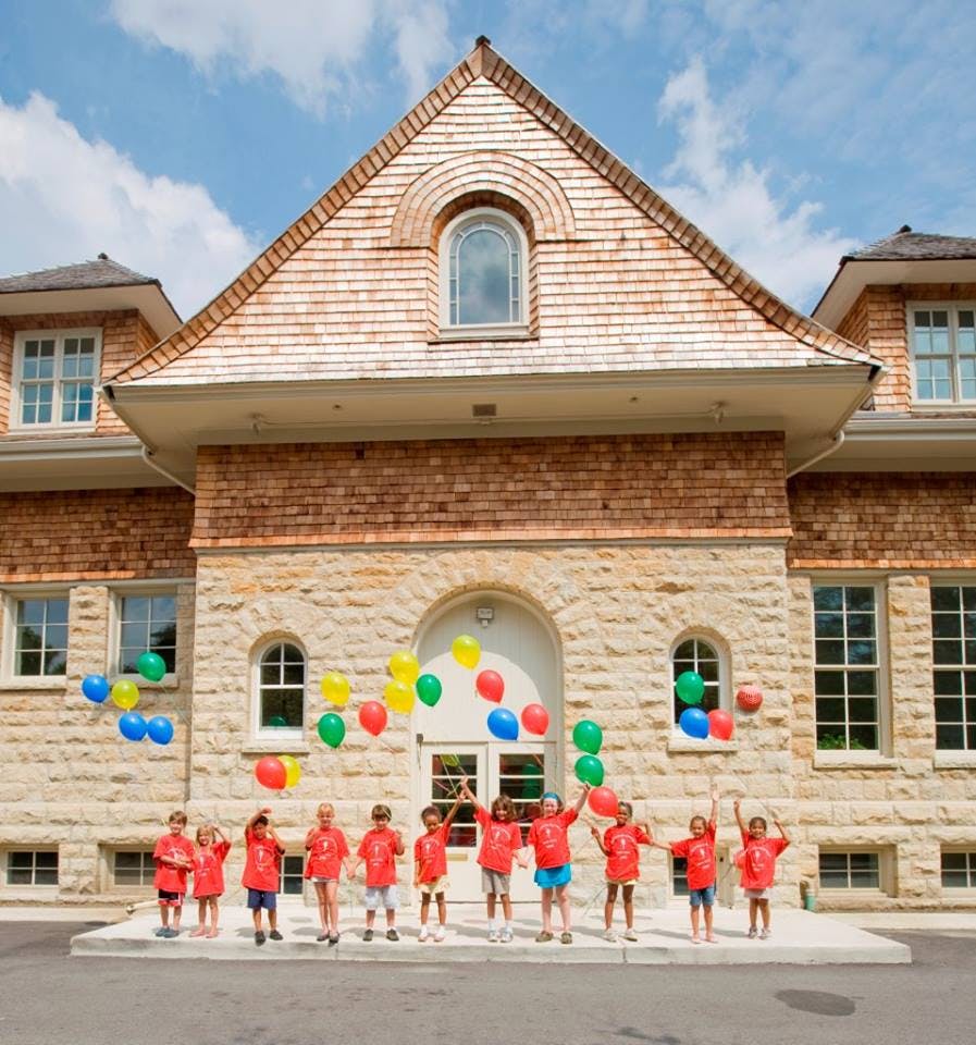 Children in red shirts releasing balloons in front of a building
