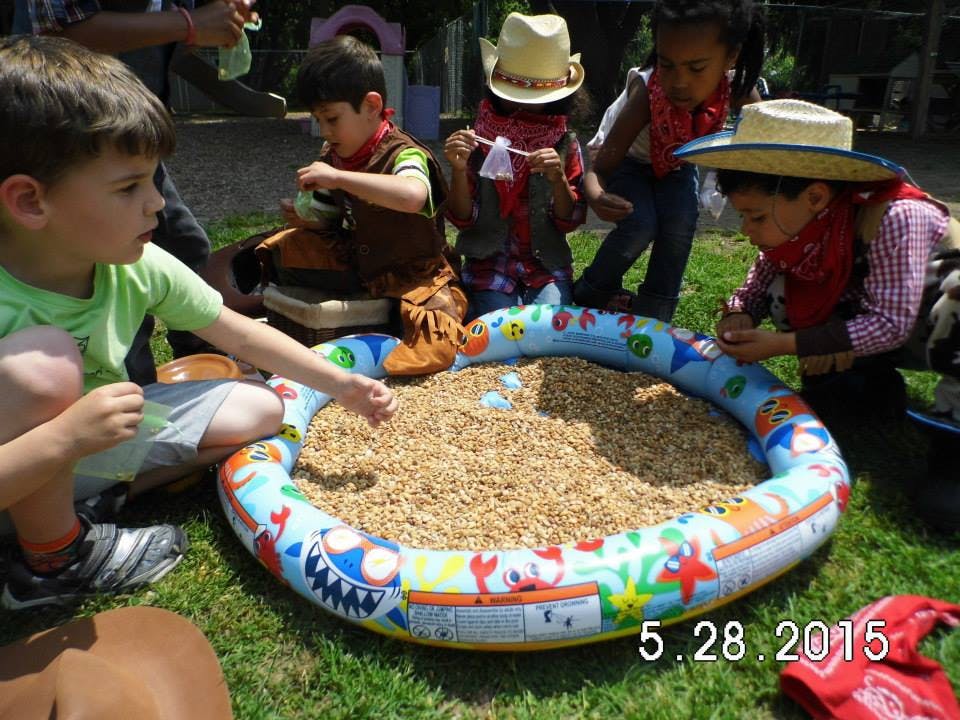 Children playing in a small inflatable pool filled with grain