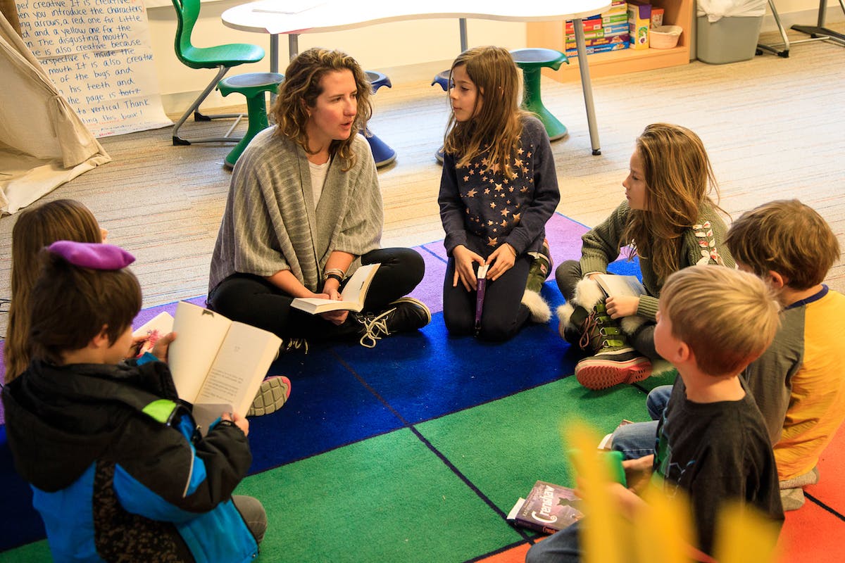 Person reading to a group of children in a classroom