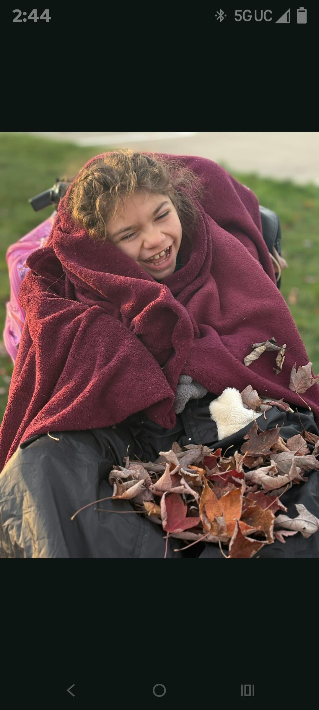 Child wrapped in a blanket with leaves on their lap