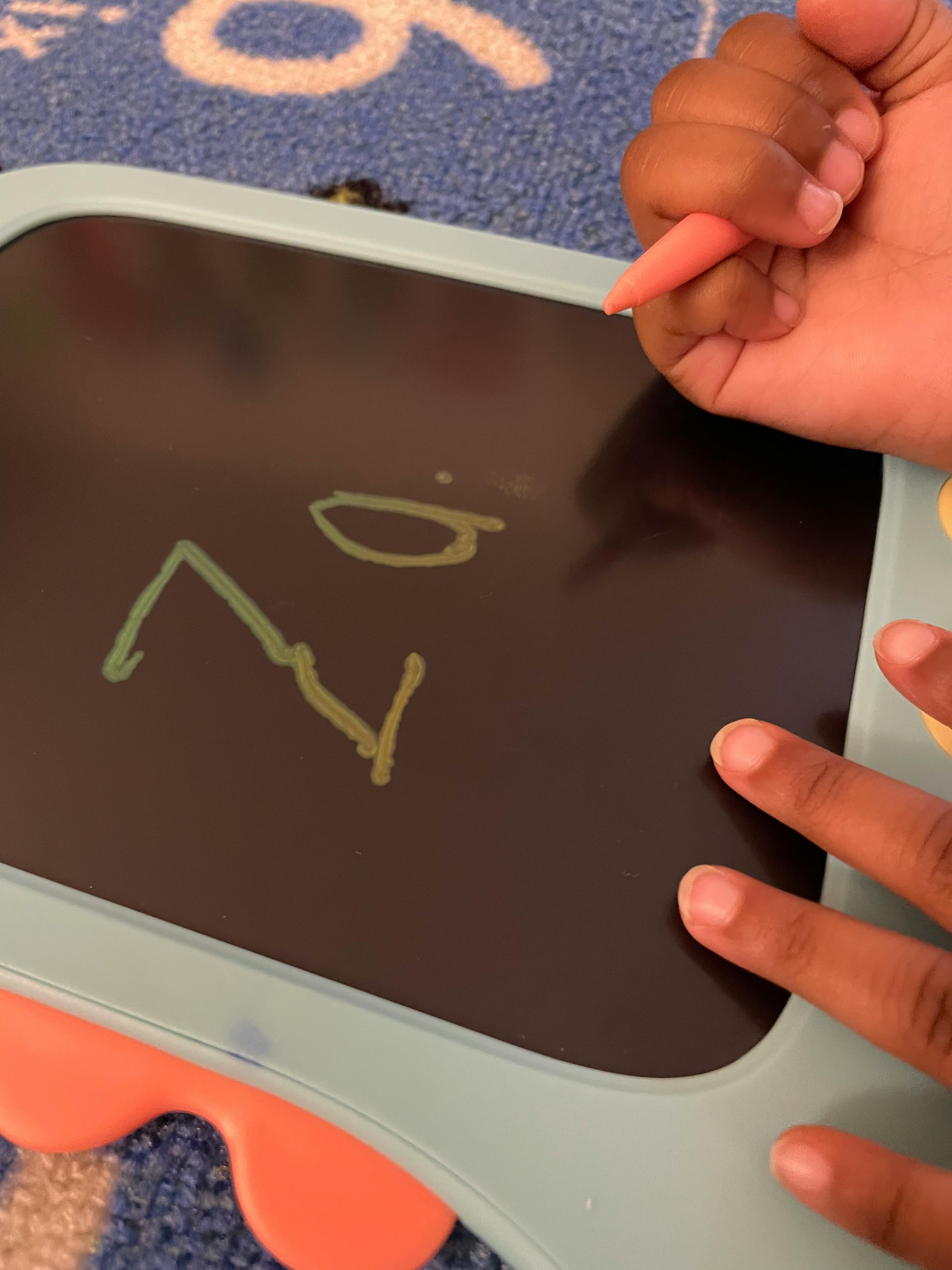 Child writing on a magnetic drawing board