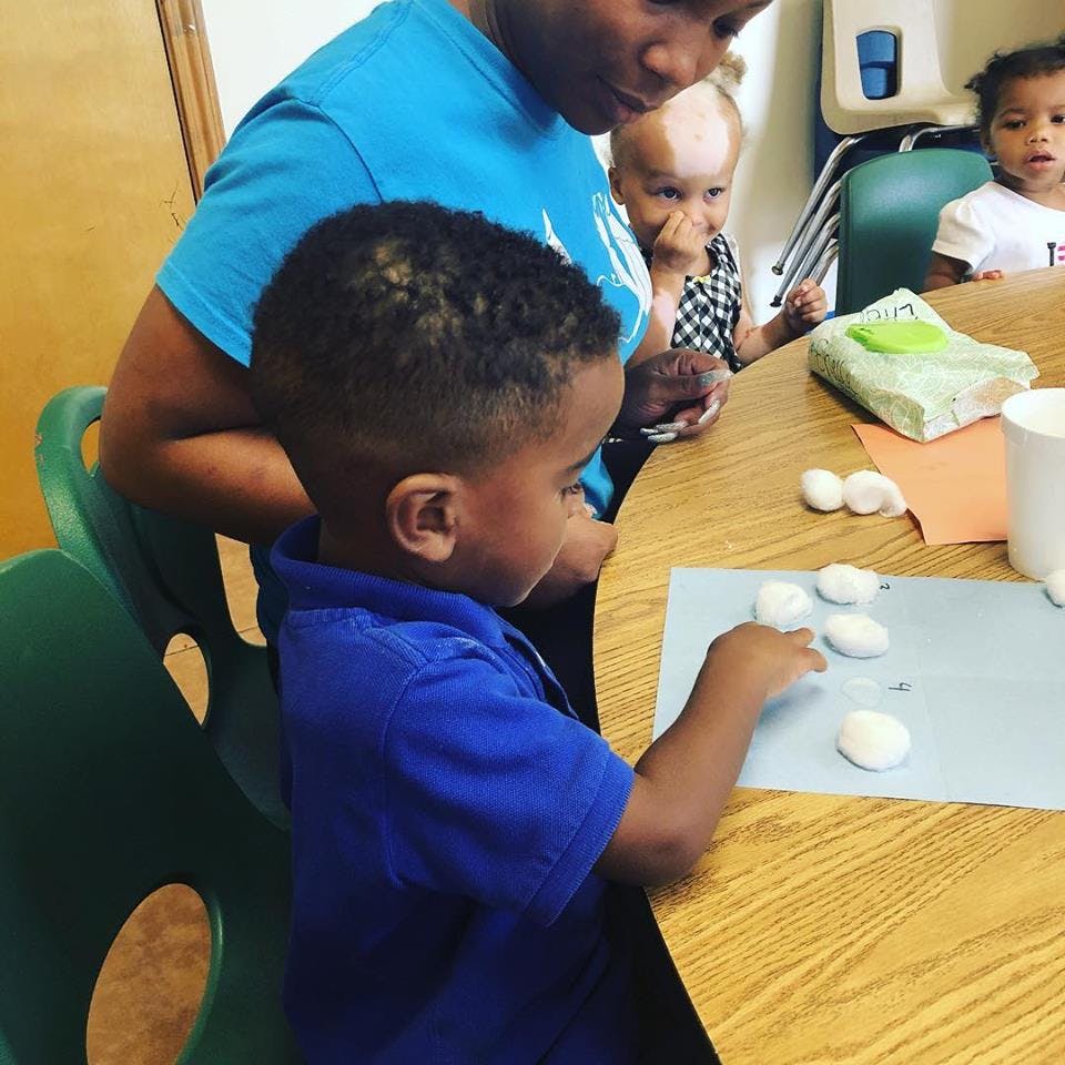 Person and child at a table with cotton balls