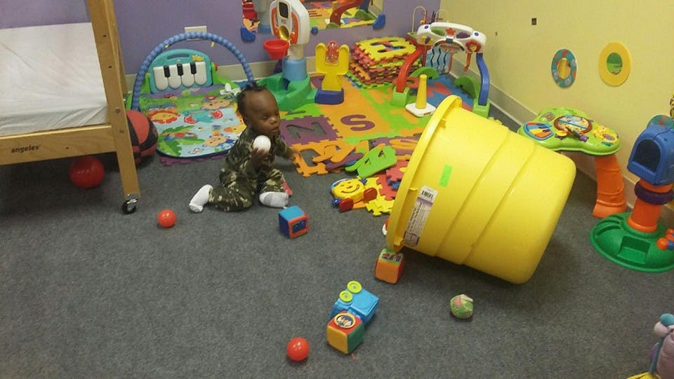 Child sitting on floor with toys and overturned yellow bucket
