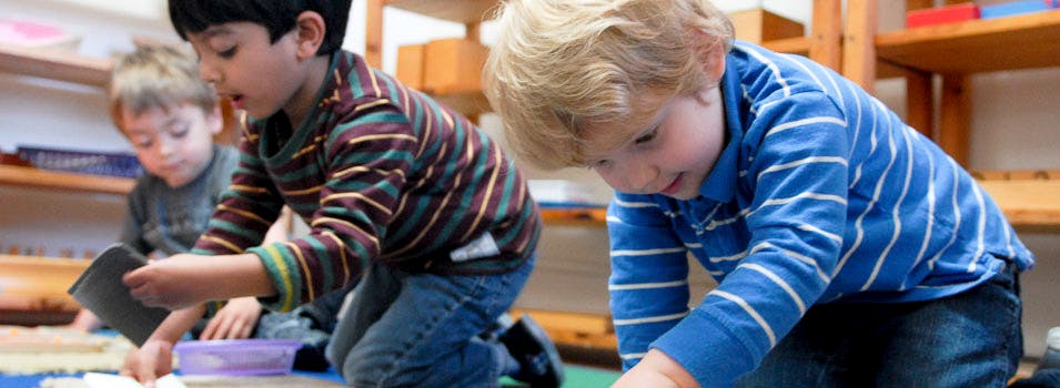 Three children playing on the floor in a classroom