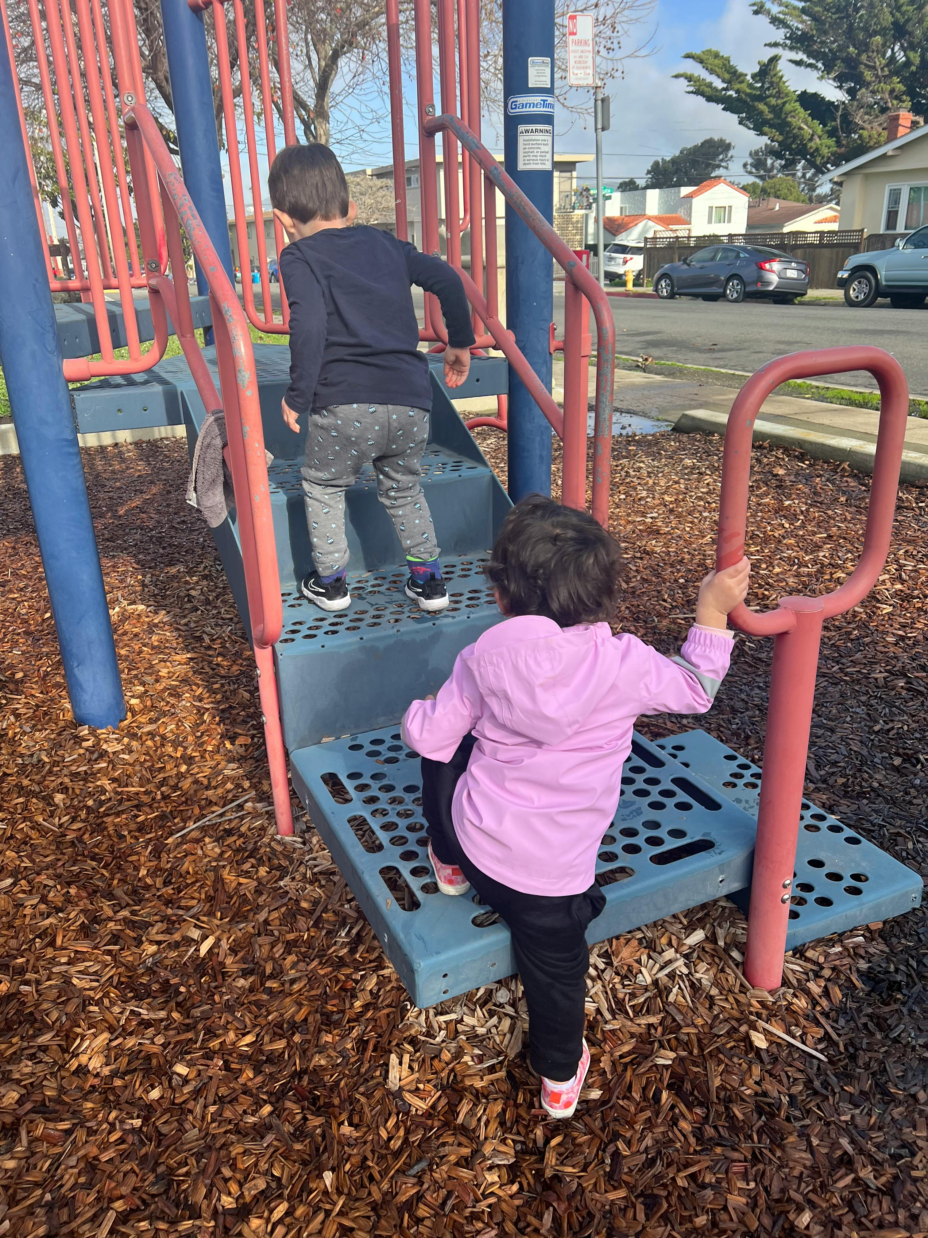 Two children climbing on playground equipment