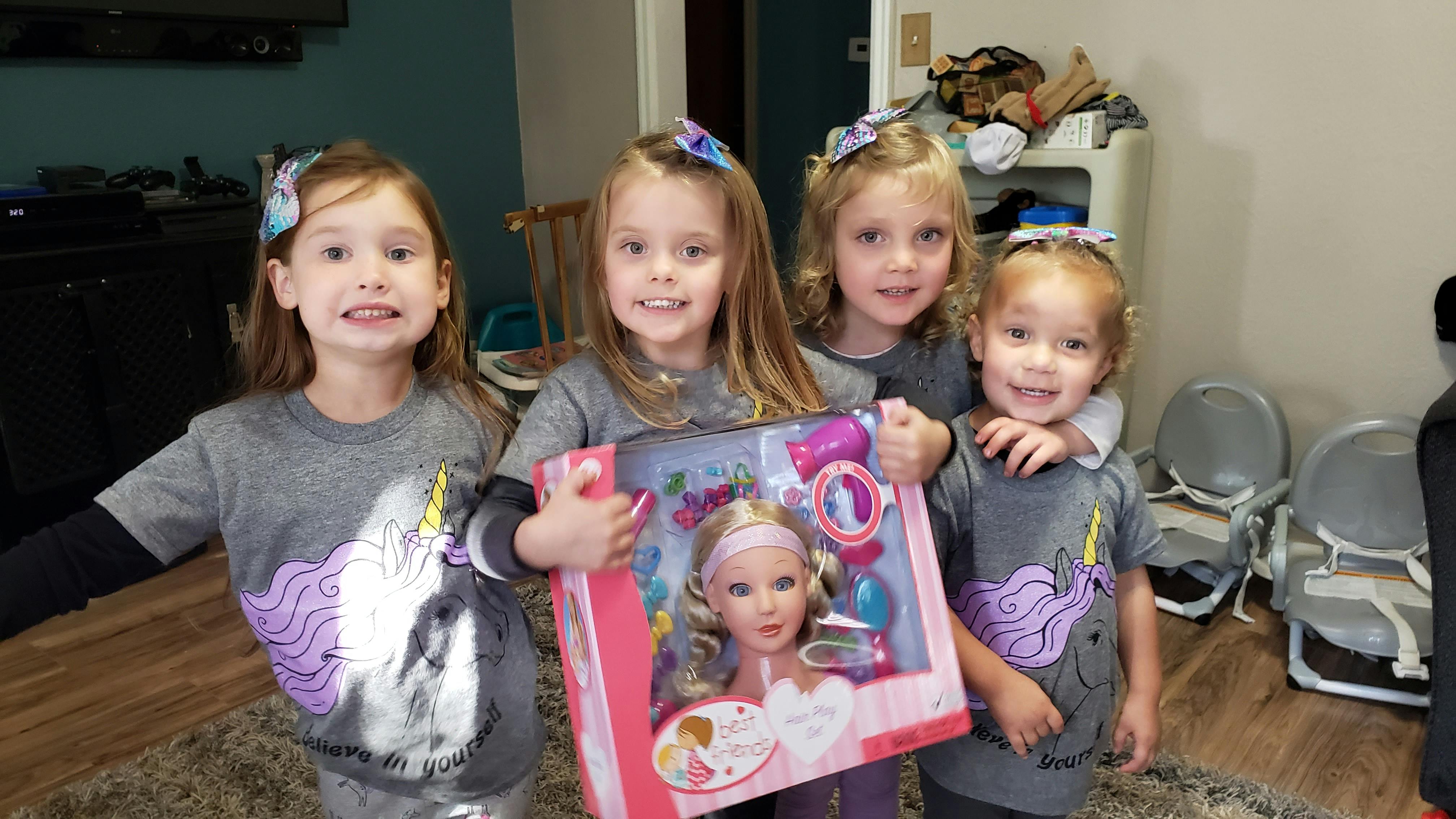Four children holding a doll in a box
